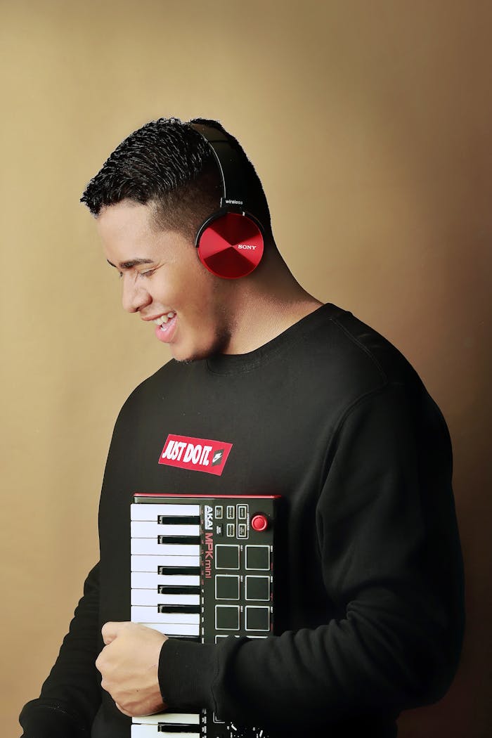 Cheerful man in headphones holding a keyboard, enjoying music indoors.